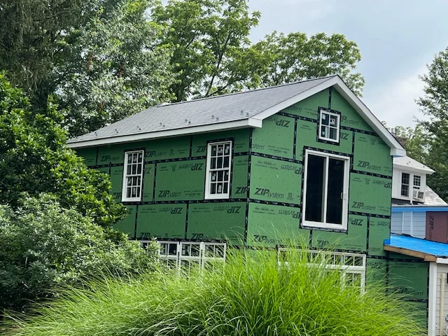 House under construction with ZIP System sheathing, surrounded by greenery, illustrating siding replacement services offered by Franco Roofing, Inc.