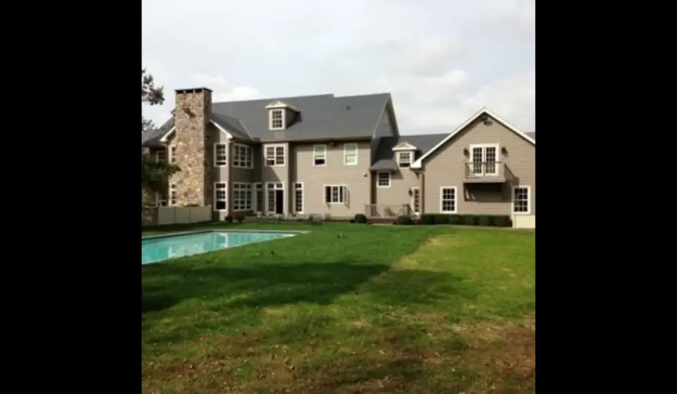 Large residential home with a well-maintained roof and green lawn, highlighting the importance of roof maintenance for homeowners.