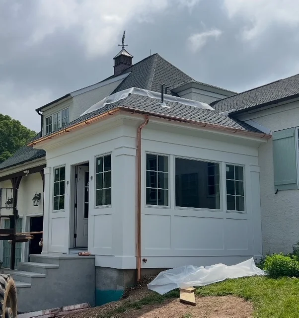 Newly constructed white siding addition on a home, featuring large windows and a copper roofline, highlighting Franco Roofing's siding services in Bucks County, PA.
