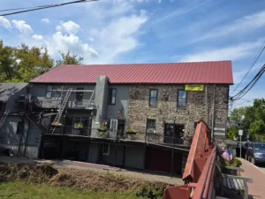 Franco Roofing project featuring a red metal roof on a stone building, showcasing craftsmanship and quality in roofing services.